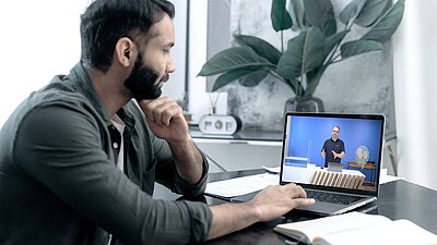 Workshop participant is in front of the laptop and is connected remotely. You can see on the screen that the trainer is standing in a room.