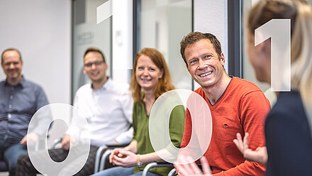 Conversation among colleagues in a chair circle for casual exchange with numbers in the foreground