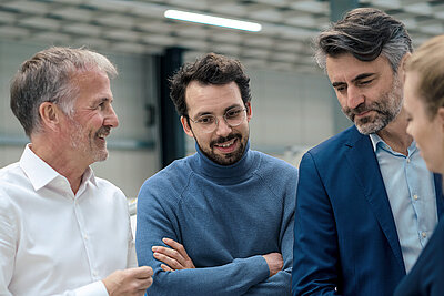 LANCOM IT Security Ecosystem Four business professionals in discussion, smiling and focused in a modern technical setting.