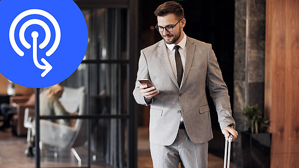 Man in a suit and with a suitcase looks at his cell phone, on the left is a blue circle with a hotspot symbol