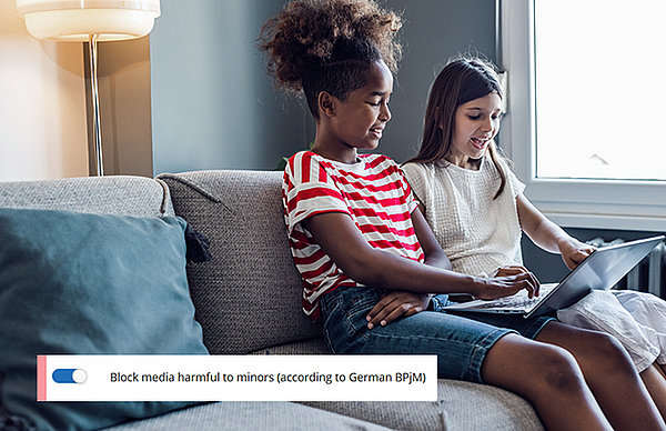 Two girls sitting on couch with tablet