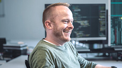 Employee sits in front of a screen and looks to the side with a smile