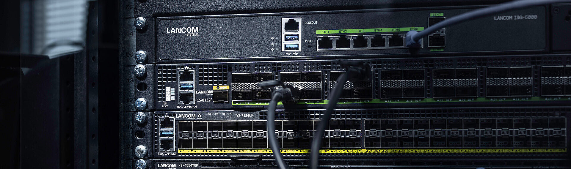 Three LANCOM switches installed in the rack with cables: core switch LANCOM CS-8132F, aggregation switch LANCOM YS-7154CF, and access switch LANCOM XS-4554XUP