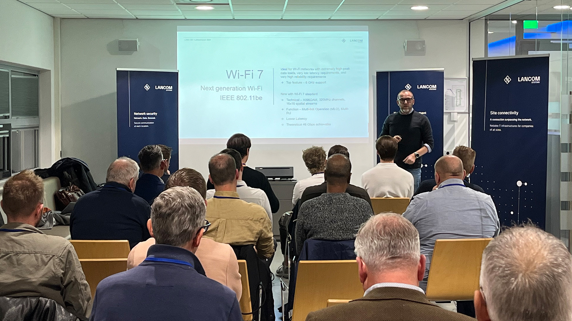 Speaker explains the benefits of Wi-Fi 7 technology to an interested audience during a LANCOM event.