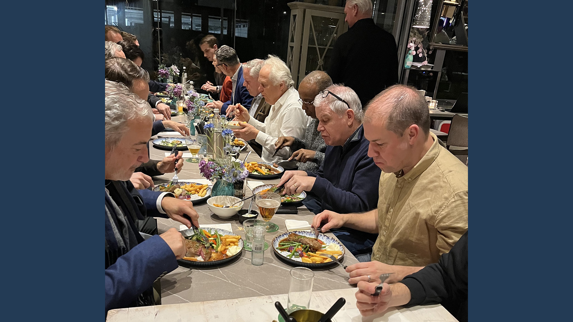 LANCOM event participants engage in conversation and dine together at a set table with decorative flowers.