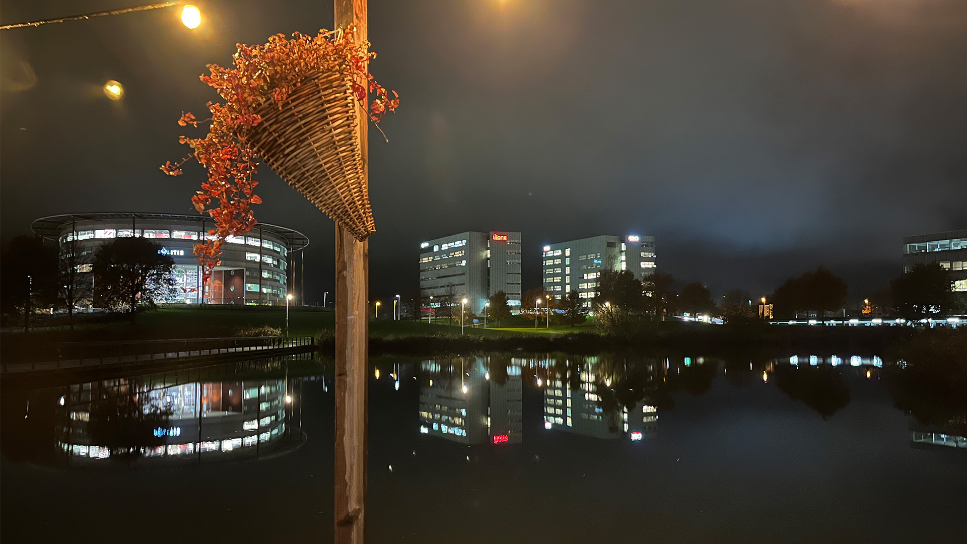 Night shot of a lake with illuminated office buildings in the background, taken during the LANCOM event in Utrecht.